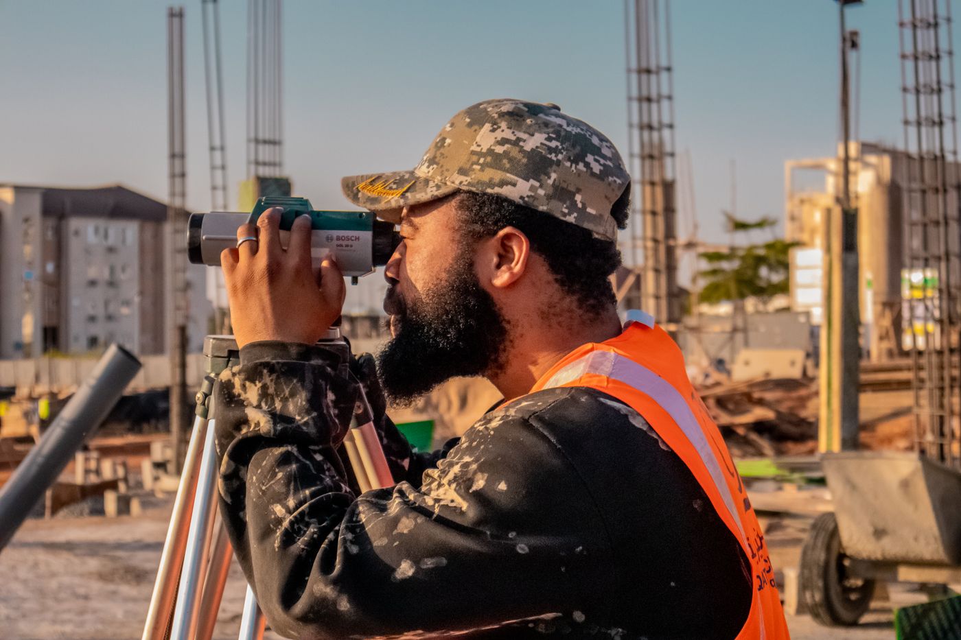 Een landmeter kijkt door een optisch meetinstrument op een bouwplaats